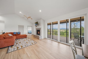 A spacious living room with a fireplace, a large sofa, and a balcony with a view. - Luxury Home on 5 Acres / Unreal Views! / Hot Tub! (Pagosa Springs)