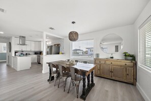 Une cuisine moderne avec des meubles blancs, une table à manger en bois et une grande fenêtre.