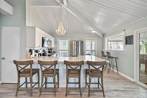 Una cocina amplia con una isla central, sillas de madera y una lámpara colgante.