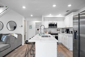 A modern kitchen with white cabinets, stainless steel appliances, and a central island.