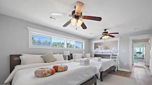 A bedroom with two beds, a ceiling fan, and a view of the outdoors.