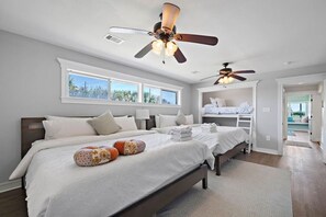 Quarto com duas camas, um ventilador de teto e vista para o exterior.