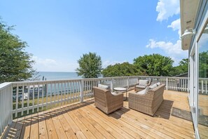 A wooden deck with wicker furniture, a white railing, and a view of the sea. - Lakefront Getaway with Pier and Pool (Lake Livingston)