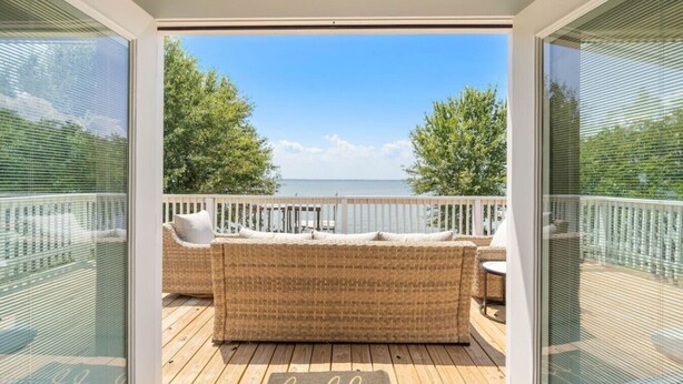 Un balcon avec des meubles en osier, une vue sur la mer et un paillasson accueillant.