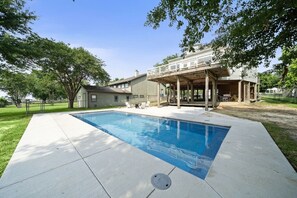 A swimming pool with a covered patio area, a house in the background, and trees around. - Lakefront Getaway with Pier and Pool (Lake Livingston)