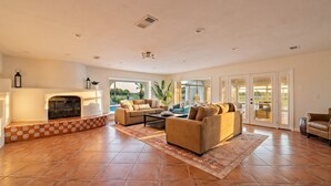 A spacious living room with a fireplace, two sofas, a coffee table, and a large window. - Villa with Private Pool, Game Room & 5+ Acres (Galveston)