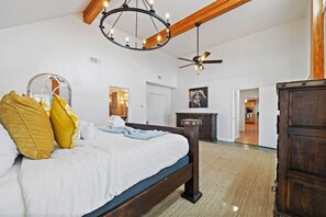 Un dormitorio con cama, ventilador de techo, candelabro y armario de madera.