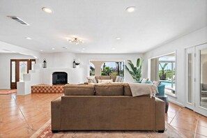 Un salón amplio con un sofá grande, una chimenea y vistas a una piscina.