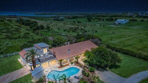 A large house with a swimming pool, surrounded by a well-maintained lawn and a view of the night sky. - Villa with Private Pool, Game Room & 5+ Acres (Galveston)