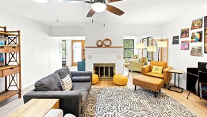 A living room with a sofa, armchair, ottoman, ceiling fan, fireplace, and wall art. - Heated Pool, Sunny Oasis, 4 bedroom, 9 beds, 4 bathrooms (Fort Lauderdale)
