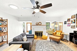 A living room with a sofa, armchair, ottoman, ceiling fan, fireplace, and wall art. - Heated Pool, Sunny Oasis, 4 bedroom, 9 beds, 4 bathrooms (Fort Lauderdale)
