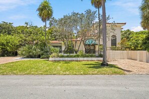 A residential property with a paved driveway, a well-maintained lawn, and a variety of tropical plants. - Heated Pool, Sunny Oasis, 4 bedroom, 9 beds, 4 bathrooms (Fort Lauderdale)