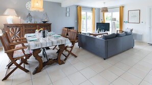 Een eetgedeelte met een houten tafel en stoelen, een bank en een televisie in een woonkamer.