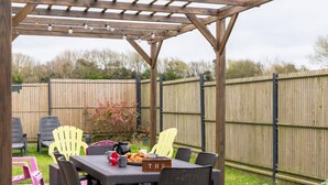 Een overdekt terras met een tafel voor twee personen, omringd door rieten stoelen.