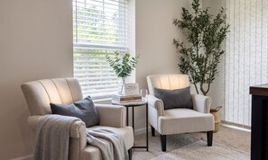 A cozy nook with two armchairs, a small table with books and a vase, and a large plant. - Lake Anna Retreat | Game Lounge | Boat Dock Access (Louisa County)