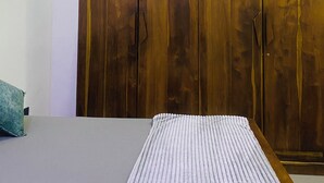 Un dormitorio con una cama, un armario de madera y un equipo de aire acondicionado en la pared.
