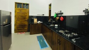 Una cocina con refrigerador, estufa, lavaplatos y armarios de madera.