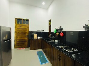 Una cocina con refrigerador, estufa, lavaplatos y armarios de madera.
