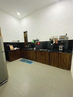 A modern kitchen with wooden cabinets, a black countertop, and various kitchen utensils and appliances.