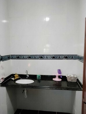 A bathroom with a white sink, black countertop, and a decorative tile border. - Hostel Arubinha (Arraial do Cabo)