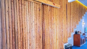 Pared de madera con tablones verticales y un suelo cubierto de moqueta azul.