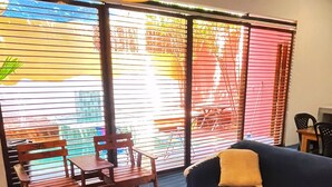 Una habitación con sofá, sillón, alfombra tejida y una mesa con mando a distancia.