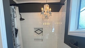 A bathroom with a bathtub, toilet, shower, and a chandelier. - Charming 3-bedroom house in amazing Hollywood Riviera section of Redondo Beach (Redondo Beach)