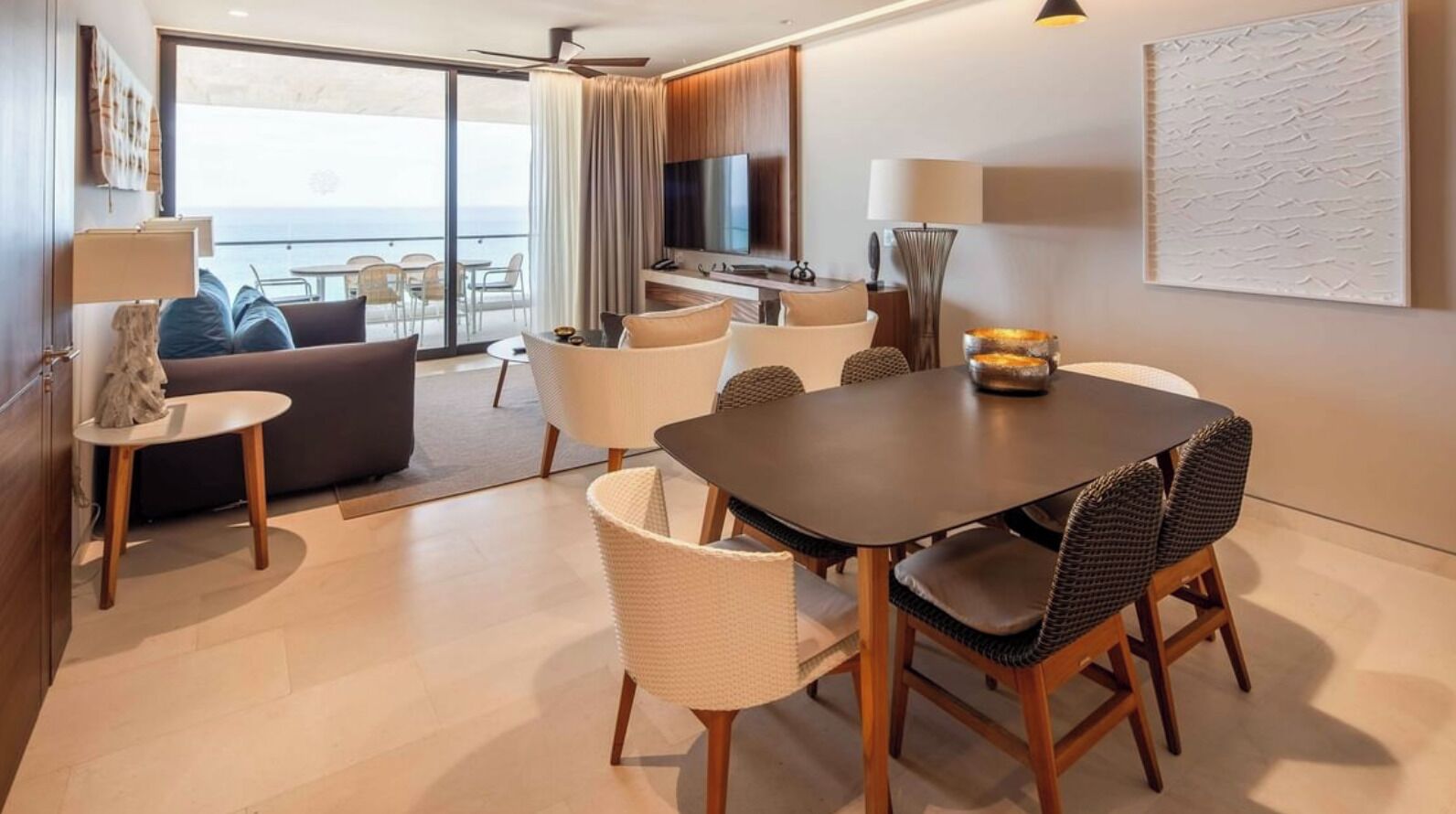 Ein modernes Hotelzimmer mit Essbereich, einer Couch, einem Fernseher und einem Balkon mit Blick.