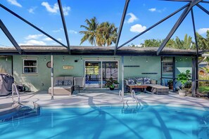 A pool area with a lounge chair, a small table, and a potted plant. - Dog-Friendly home with quick access to the beach and downtown with heated pool. (Stuart)