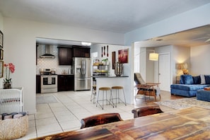 A modern kitchen with a central island, stainless steel appliances, and a dining area with a wooden table and chairs. - Dog-Friendly home with quick access to the beach and downtown with heated pool. (Stuart)