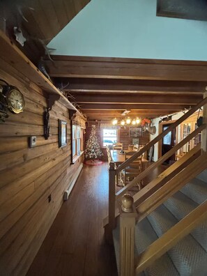 A wooden interior with a staircase, a Christmas tree, and a dining area. - Log Cabin - Hot Tub - Near Kalahari & Camelback (Newfoundland)