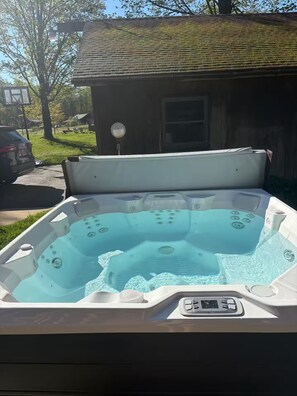 Ein Whirlpool mit Bedienfeld, im Hintergrund ein Haus und ein Baum.