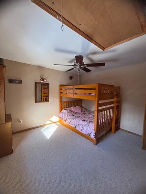 Habitación con literas, ventilador de techo, un espejo y una pequeña planta.