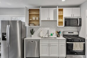 A modern kitchen with stainless steel appliances, white cabinetry, and a built-in microwave.