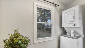 Een wasserij met een raam, een wasmachine en een plant.