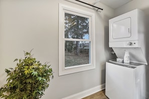 A laundry room with a window, a washing machine, and a plant.