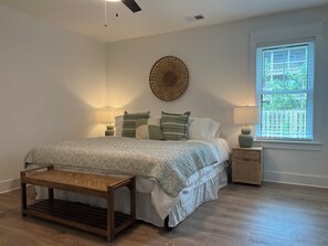 Ein Schlafzimmer mit Bett, Nachttischen, einer Wanddekoration und einem Fenster.