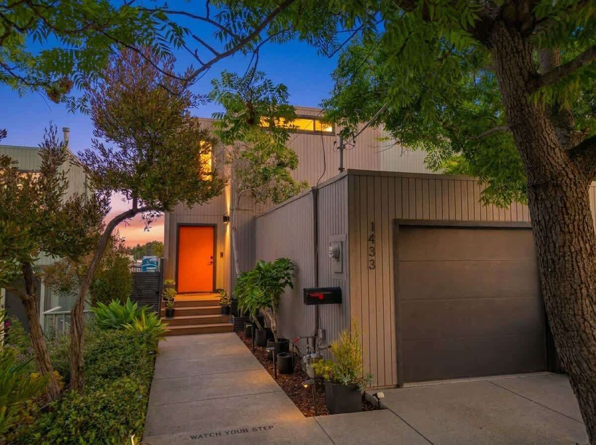 Un bâtiment moderne doté d’un garage, d’un hall d’entrée bien éclairé et d’un chemin menant à la porte.