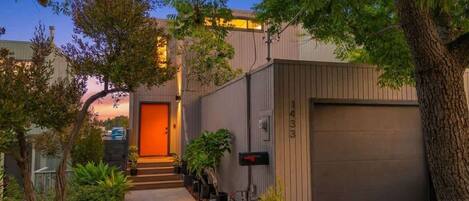 A modern building with a garage, a well-lit entrance, and a pathway leading to the door.