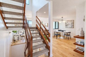 Eine Treppe mit Holzwangen und Teppichstufen führt zu einem Essbereich mit rundem Tisch und Stühlen.