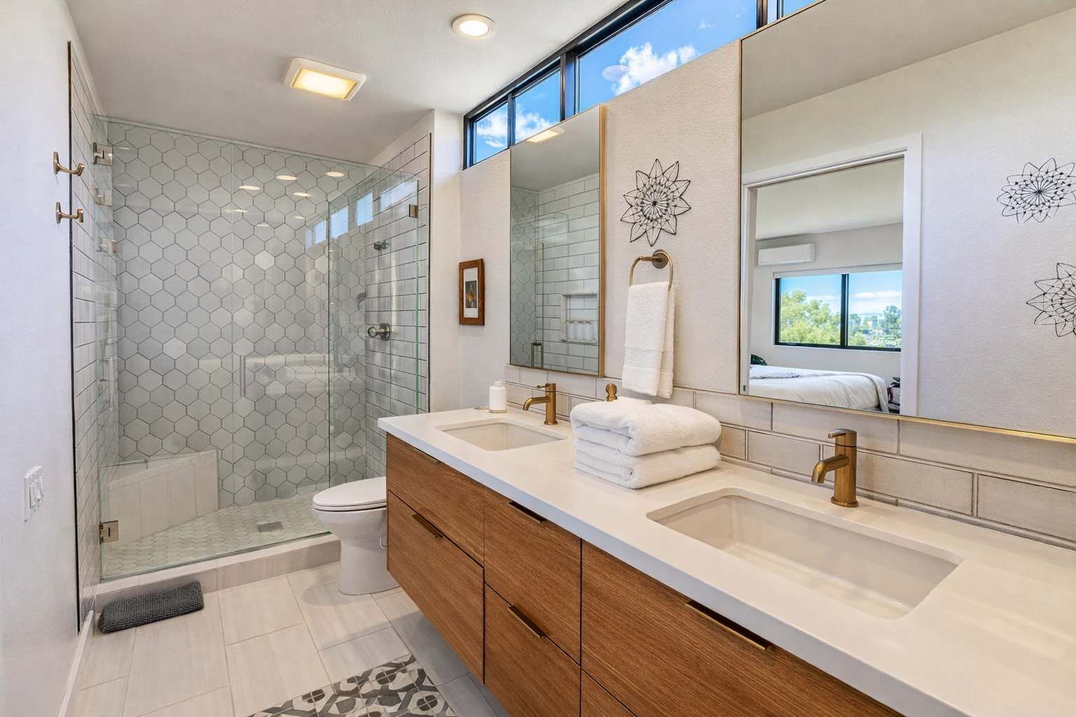 Une salle de bain moderne dotée d’une douche à parois de verre, de deux vasques et d’un grand miroir.