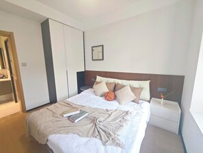Une chambre à coucher comprenant un lit, une table de chevet, une commode, une armoire et un tableau encadré accroché au mur.