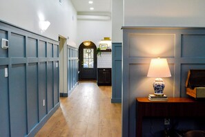 Ein Flur mit Holzboden, einer Tür mit Fensterteil und einer Wandlampe.