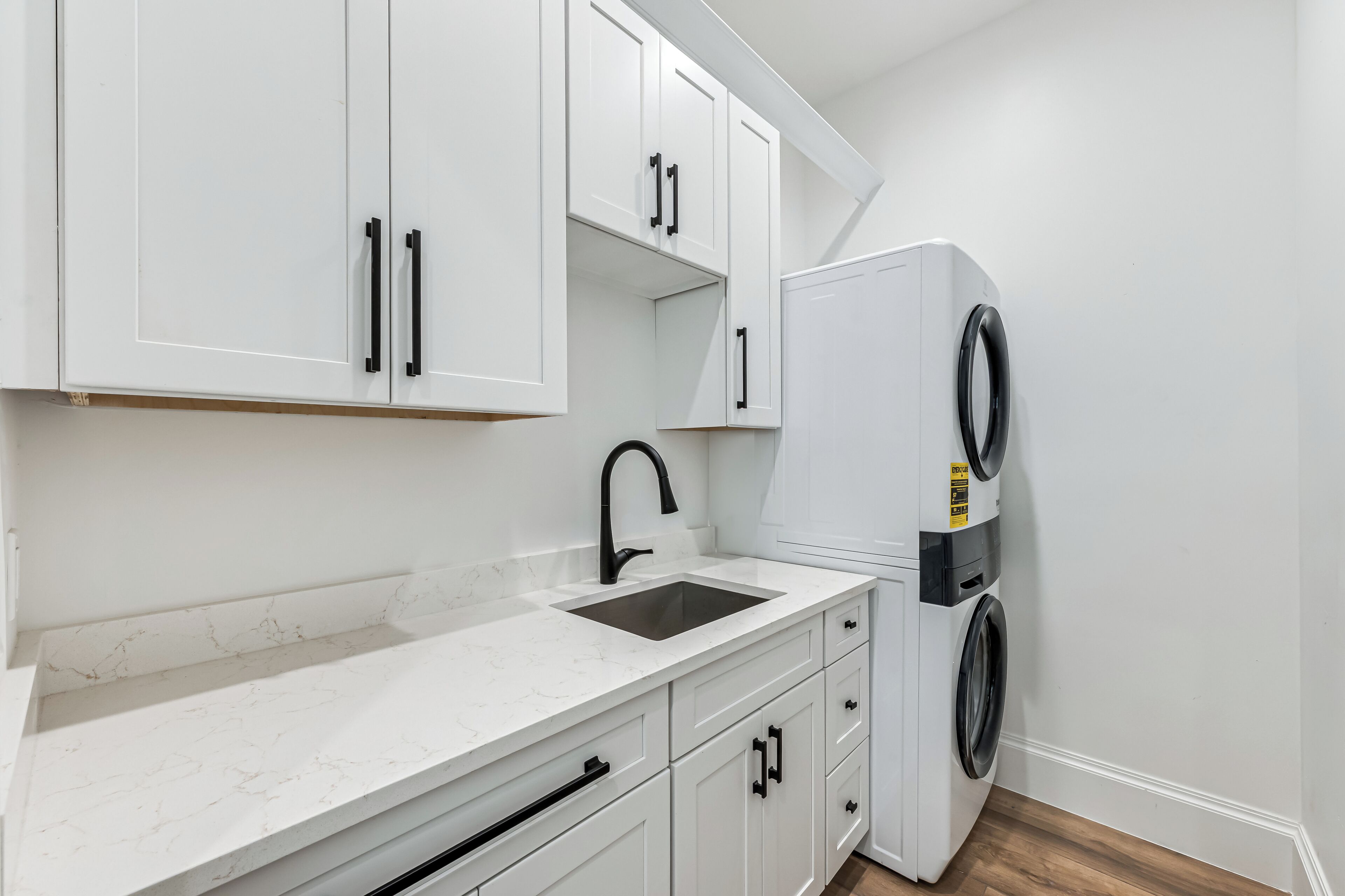 A kitchen with white cabinets, a sink, a black faucet, and a washing machine.