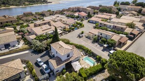 Et kystnære boligområde med huse med terracotta-tag, en swimmingpool og en strand i baggrunden.