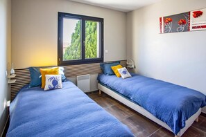 Ein Schlafzimmer mit zwei Betten, einem Fenster und einem Wandbild.
