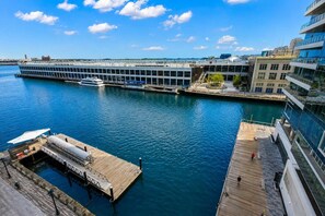 Ein Hotel direkt am Wasser mit einer Anlegestelle, ein großes Gebäude mit Glasfassade und blauem Himmel.