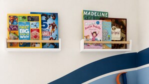 Een kinderboekenkast met boeken en opbergbakken voor spelletjes en activiteiten.
