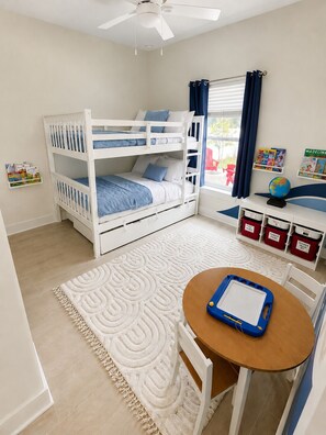 Ein Kinderzimmer mit Etagenbetten, einem Schreibtisch und Staufässern.
