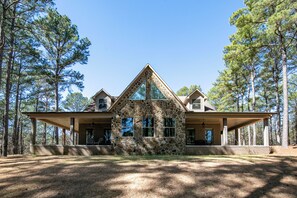 A stone house with a large porch, surrounded by tall pine trees. - The Perfect Oxford Basecamp for Families, Friends & Rebels (Water Valley)